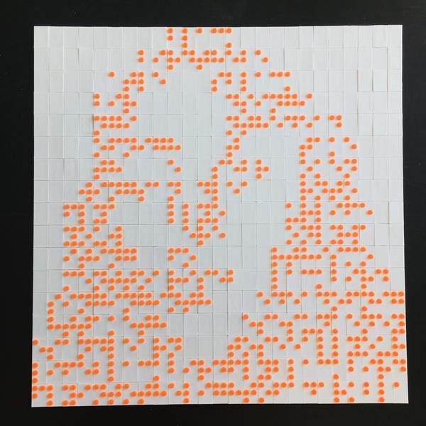 Das Bild zeigt ein weißes Bildartiges schmales Objekt vor einem schwarzen Hintergrund, das gleichmäßig in Linien angelegte neonorange Punkte enthält. Man erkennt, dass das Objekt aus kleinen weißen an Legosteine erinnernde Plättchen zusammengesetzt ist, die Brailleschrift ergeben.
