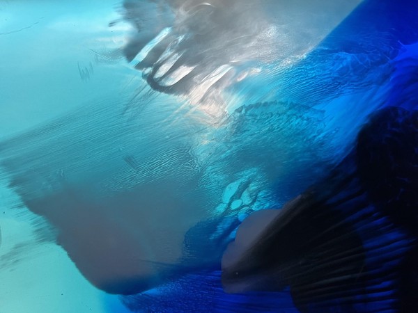 Das Bild zeigt eine abstrakte blau-weiße leuchtende Farbkombination in verschiedenen Abstufungen, die an das Meer erinnert.