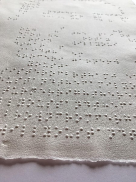 Das Bild zeigt die Nahaufnahme aus schräger Position eines weiteren in Punkten geprägten Portraits, des bekannten Bildes von George Floyd. Man erkennt hier, dass die Prägepunkte Braillebuchstaben sind.