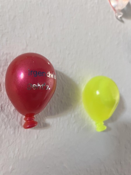 Das Bild zeigt eine Detailaufnahme von drei der kleinen Luftballons. Auf einem kann man lesen: irgendwie geht’s