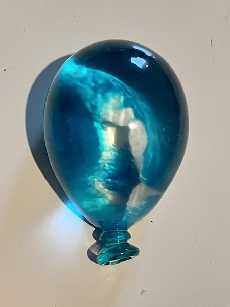 Das Bild zeigt einen einzelnen kleinen Luftballon, der gläsern schimmert und dessen Gestaltung an ein Meer erinnert. 