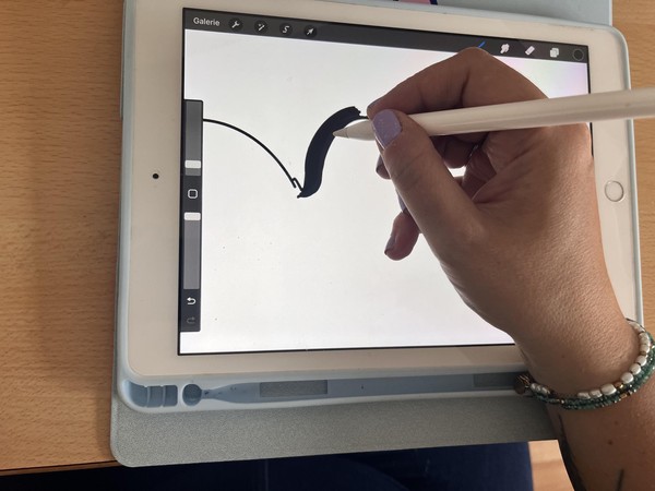 Das Bild zeigt eine Hand, die auf einem Tablet zeichnet.